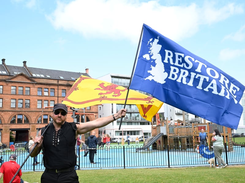 A protester waves the Saltire and a 'Restore Britain' flag during an anti-immigration protest, organised by Unite the Clans Scotland, in Glasgow.