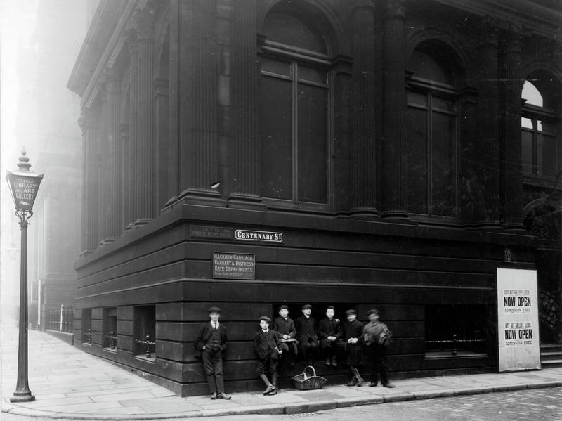 Close-up view of the corner of the Municipal Buildings, at the time housing the Central Library, Art Gallery and Civic Offices. A group of boys are seen standing or sitting on railings at the front. Pictured in December 1907.