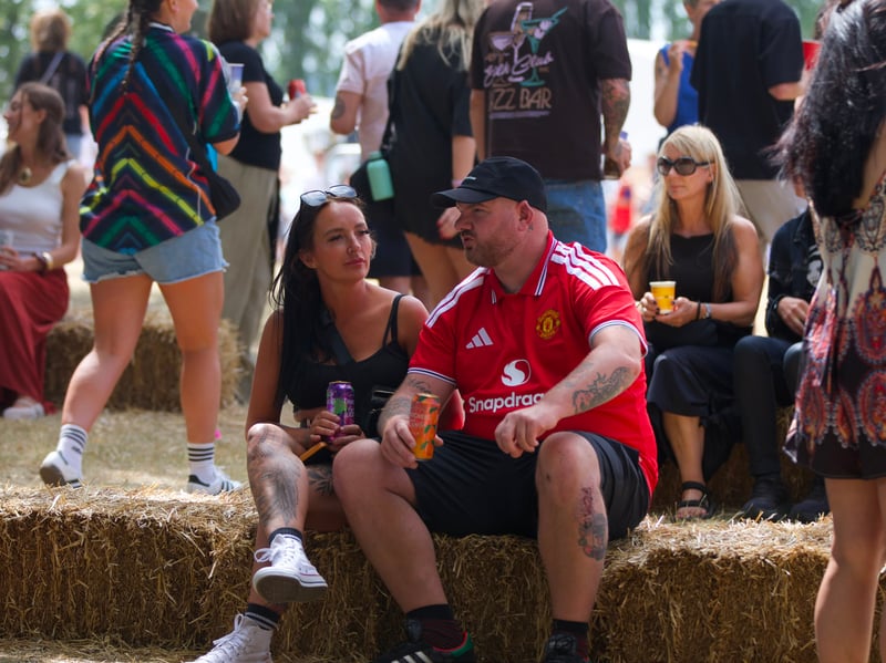 These two festival goers stop for a moment, and take in the festival atmosphere from a hay bale