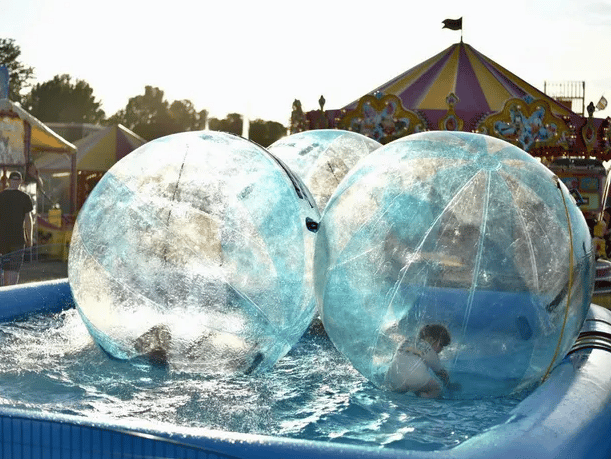 Children playing in large water orbs.
