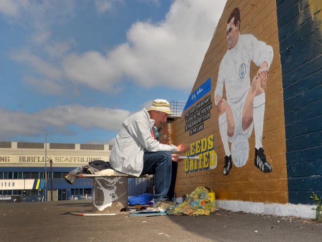 Artist Robert Endeacott puts the finishing touches to Bobby Collins that completes his mural for the Leeds United themed car wash