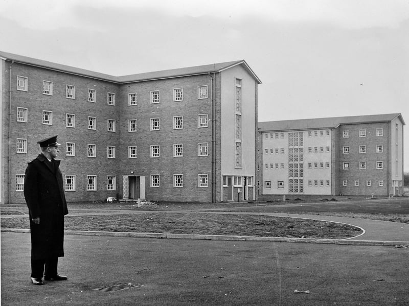 A solitary prison officer in full uniform stands watch before the stark, modern brick accommodation blocks of Stoke Heath. Captured around the time the facility officially opened on 6 April 1964, the image shows the new institution near Market Drayton in its earliest days. Originally established as a secure Borstal to house young offenders, the complex represented a major expansion in regional penal infrastructure during the mid-1960s. Do you remember when Stoke Heath Borstal was first built in 1964, or do you recall its early years in the local community?