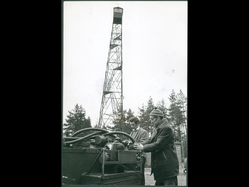 Two workmen inspect fire equipment in March 1970 near the towering fire watch tower on Cannock Chase. Soaring above the surrounding pines and heathland, the steel lookout tower served as a vital early warning station to spot smoke and fires across the countryside. The dedicated safeguards helped protect an essential natural haven cherished by generations of local walkers, families, and nature lovers. Do you remember seeing the fire watch tower on Cannock Chase during family visits? Did you ever spot the lookout structure standing tall above the tree line in the area?