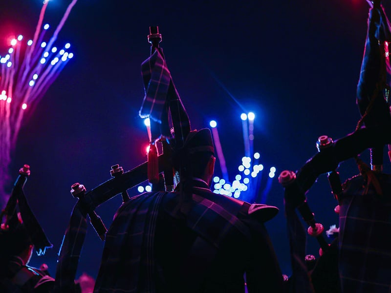 Pipers look on as fireworks light up the sky.