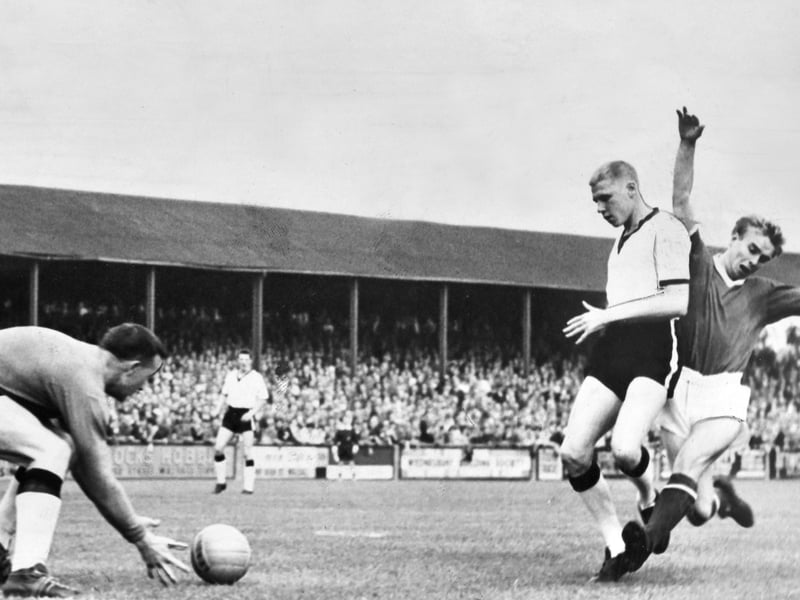 Action unfolds in front of a packed terrace as Walsall's Mike Pearson stretches to fire off a shot against Rotherham on September 22, 1962. Hindered under pressure by defender Cassidy, Pearson couldn't quite cleanly get hold of the ball, allowing Rotherham goalkeeper Ironside to safely swoop in and clear the danger. This tense moment featured in the iconic Sporting Star (affectionately known to fans as 'the pink') later that very evening, capturing the passion and gritty action of Second Division football at the Saddleback Stand end of Fellows Park. Were you in the stands at Fellows Park for this clash with Rotherham back in September 1962?