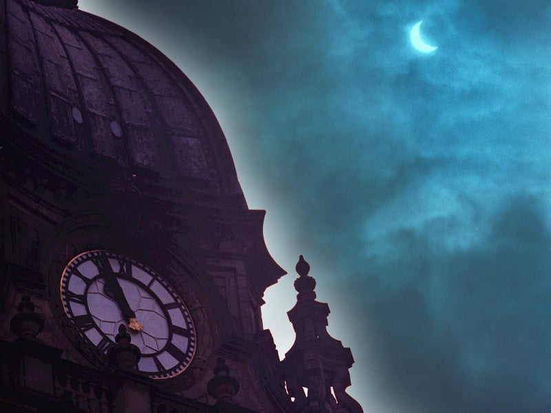 The eclipse visible alongside the silhouetted roofline and spires of Leeds city centre during the mid-morning darkness of August 11, 1999.