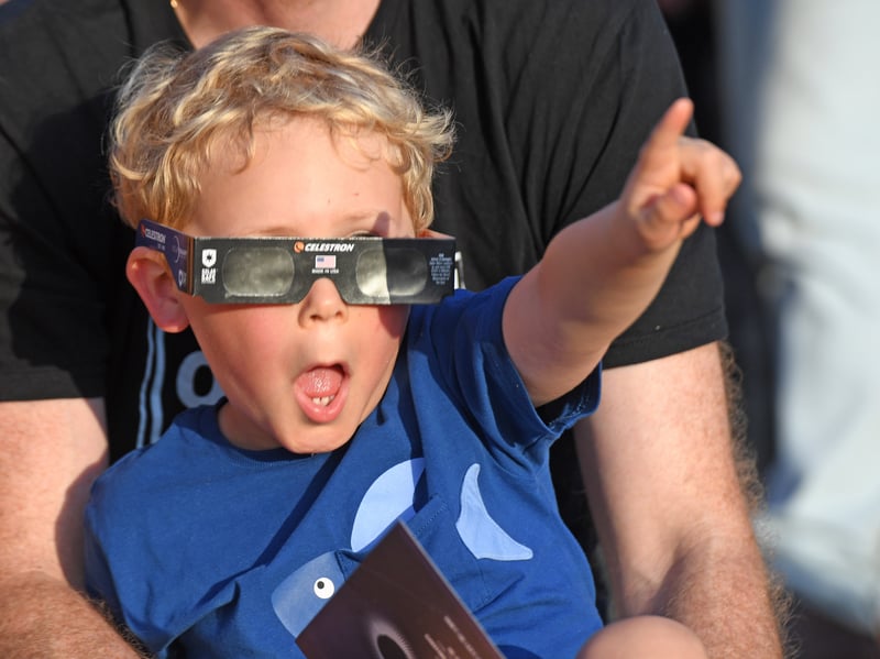 Pictured a youngster views the eclipse through special glasses.