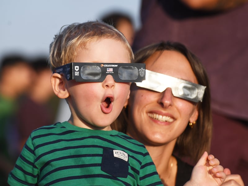 Pictured a youngster views the eclipse through special glasses.