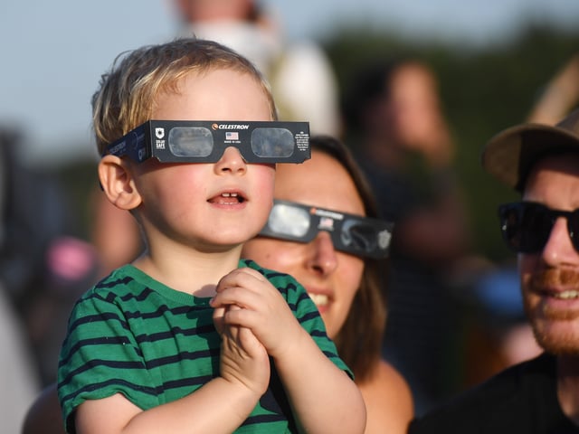 Pictured a youngster views the eclipse through special glasses.