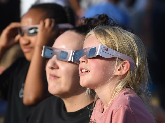Pictured viewing the eclipse through special glasses.