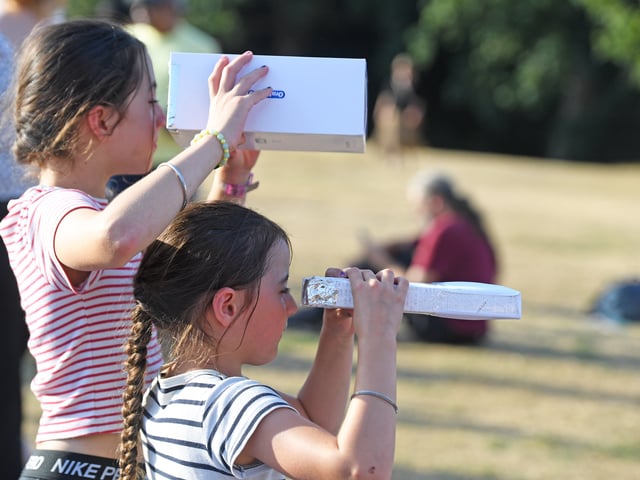 Pictured viewing the eclipse through home made contraptions .
