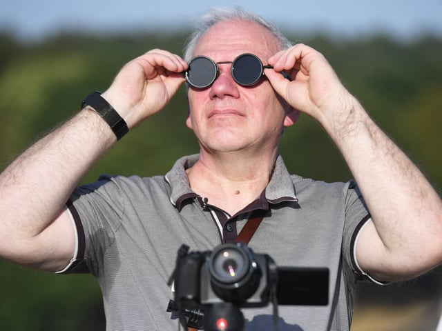 Pictured viewing the eclipse through special glasses.