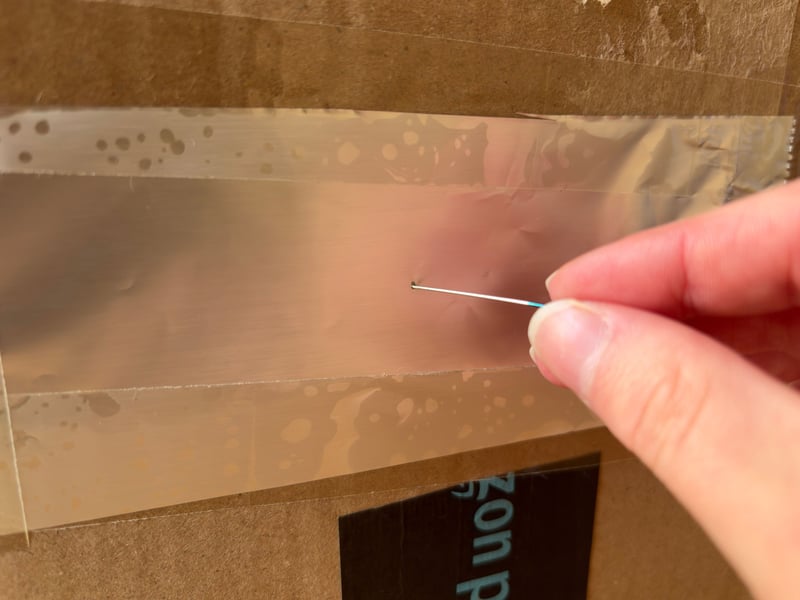 Whether you use tinfoil or paper, take a pin and carefully pierce the material. The hole may be large or small, but it’s important to note that this is what will determine how large the projection will be. Here I used a sewing pin, but thumbtacks or items such as safety pins will also work.