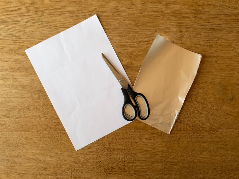 Grab either a sheet of paper or tinfoil and cut it to be slightly larger than the hole in the box. This is so you can tape it down easily.