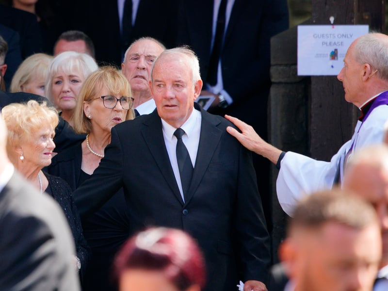 Husband Robert Sullivan receives a consoling hand on the shoulder from a member of the clergy.