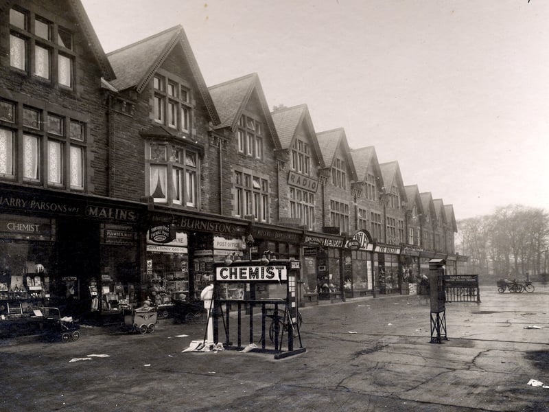 Parade of shops on Street Lane in December 1932. On the left no 59 are Harry Parsons, chemist and Raymond Malins, ironmonger, sharing a shop entrance. To the right, no 61 is Fred Burniston newsagent and Post office. Babies in their prams are outside the shops. An electric sign for the chemist is on the pavement.