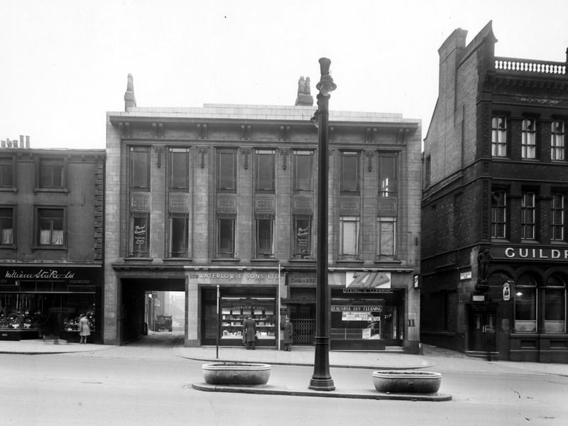 The South West side of The Headrow in December 1948 showing number 107 W. Strike Ltd seedsmen, entrance to Butts Court, 109 Waterlow and Sons Ltd. stationers, number 111 entrance to Guildford Chambers with M. Ramsden hairdresser above, number 113 Zip French cleaners. Next is the entrance to Green Dragon Yard then number 115, Guildford Hotel and pub.