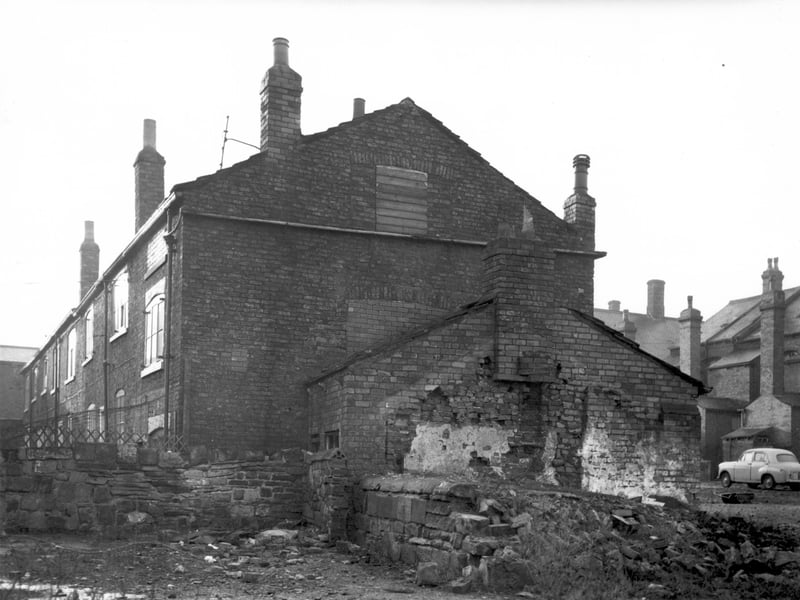 Side elevation of properties on Second Fold off Chapel Lane. The gable end of number 24 is visible in the centre of the view, originally there were two outbuildings to the side of the property, only one remains. These properties were due for demolition as part of the Armley slum clearance programme. The rear of houses on Wesley Road are visible in the background to the right.