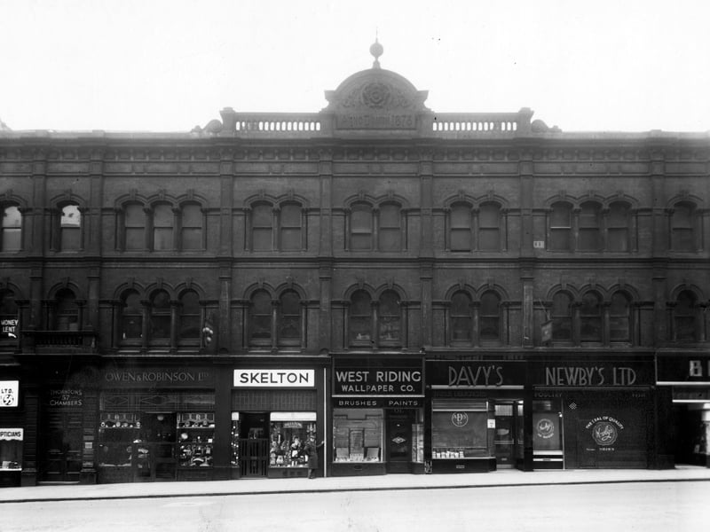 Numbers 57 to 65 on the South West side of The Headrow in December 1949. Premises include, number 57, Thorntons Chambers, number 59, Owen and Robinson, jewellers, number 61, Skeltons Hosiers, number 61a, West Riding Wallpaper Co., number 63, A. Davy and Sons Ltd. provisions, number 65, Newbys Ltd, fish and poultry. A man stands outside Skeltons