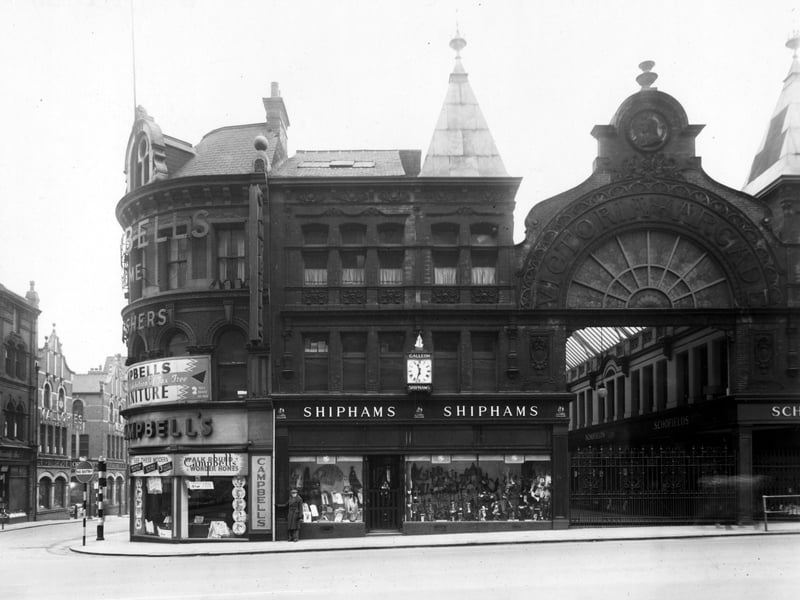 Looking at Lands Lane and Victoria Arcade from the South West side of The Headrow. On the corner is 'Campbell and Co, Furnishers', then 'H.G.Shipham Ltd. Hosiers'. Schofields Department Store can be seen down Victoria Arcade, which has its metal gates shut
