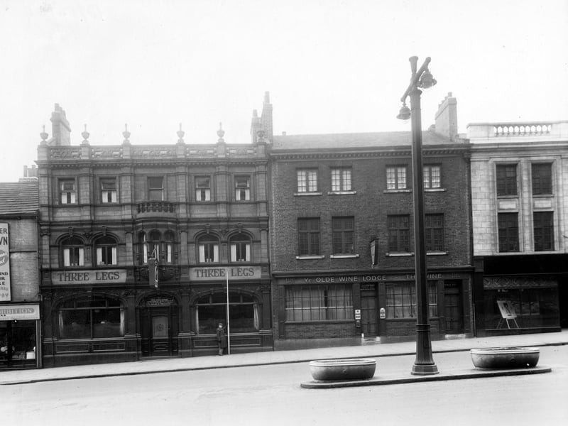 The south side of The Headrow showing two public houses. To the left is no. 9, The Three Legs pub. To the right is nos. 11/13 The Vine, previously Ye Olde Wine Lodge. On the far right is the Ministry of Labour at number 15. A man stands with a measuring stick outside the Three Legs. Pictured in December 1949.