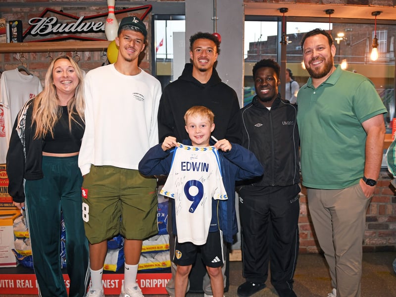 Tarik Muharemović, Willy Gnonto, and Ethan Ampadu pose for a snap with a young fan holding a LUFC shirt with Edwin on the back