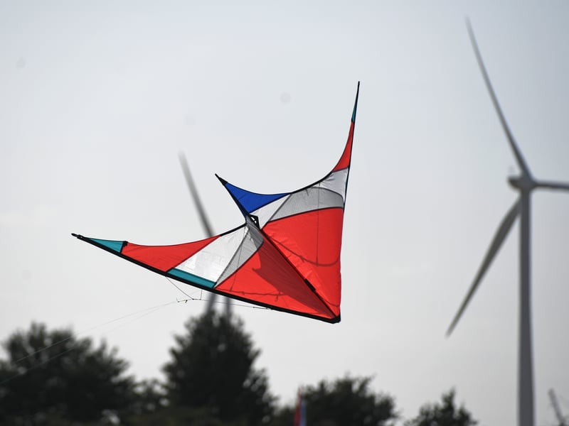Kites in the sky with a backdrop of wind turbines.
