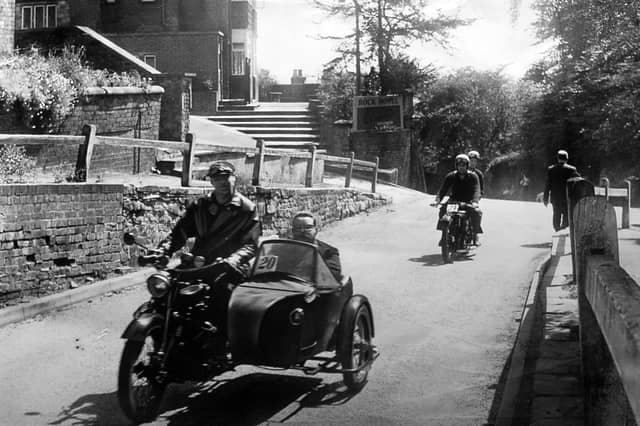 A 1928 AJS combination driven by R Jordan of Penn with John Priest, the owner, in the sidecar, motors past the Rock Hotel at Tettenhall, Wolverhampton. The print has a date stamp for May 18, 1964, but we haven't been able to identify this event, although as the magnificent machines have numbers on clearly it is some sort of rally or race.