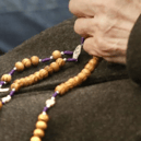 Stock image of a person holding rosary beads