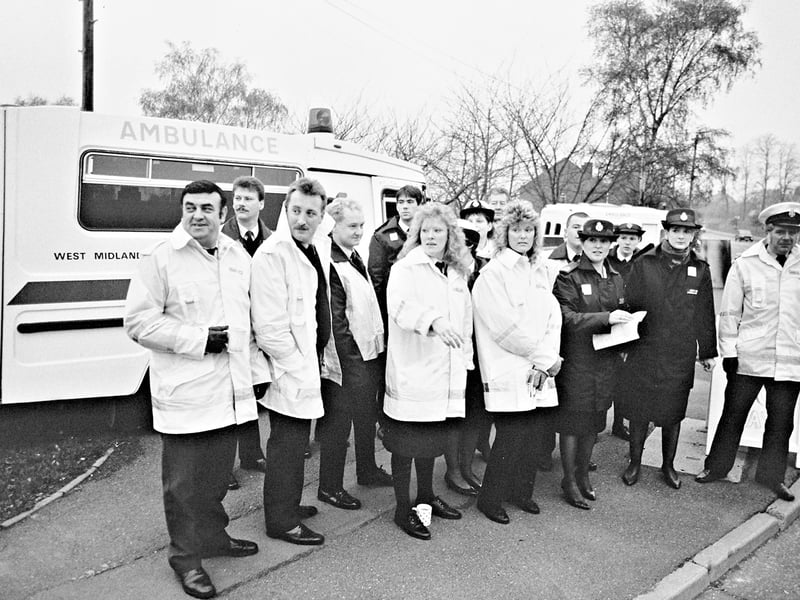 Paramedics and controllers gather on the picket line at Wordsley Ambulance Station in November 1989 during a dispute over pay, while continuing to respond to emergency calls. An ambulance forms the backdrop to the scene, highlighting the difficult balance between industrial action and caring for the public. Do you remember the ambulance dispute of 1989, or these picket lines around the area?