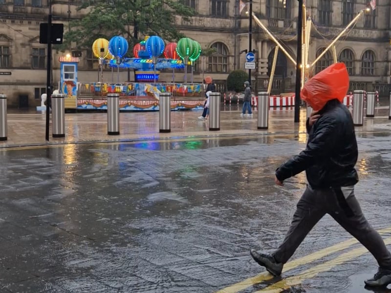 A pedestrian comes up with an improvsed solution to staying dry near the top of Fargate, Sheffield. Photo: Iconic Media
