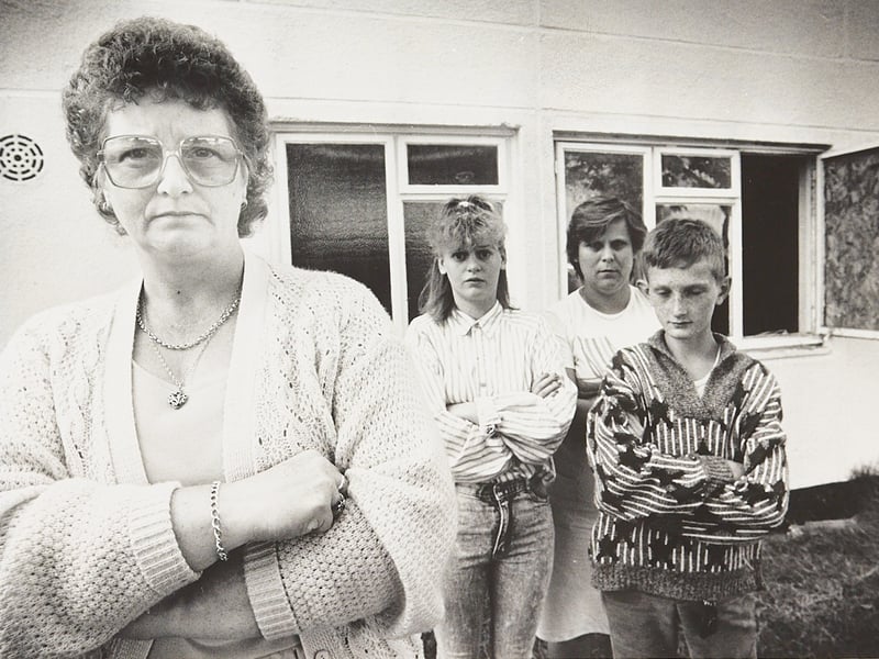 A family stands outside their flat in August 1989, looking far from happy – but almost everything else about the picture is a mystery. The only clue on the back is the handwritten description "dirty flat", with no location or further details recorded. Can you help us identify where this was taken or tell us what might have been happening?