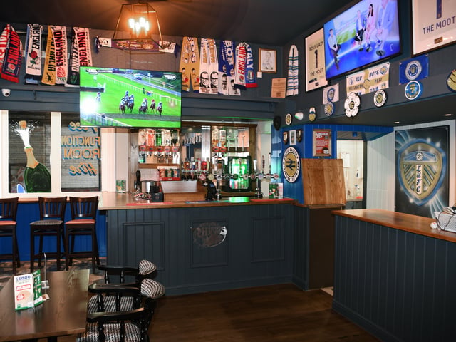 The space is filled with Leeds United memorabilia including vintage flags, scarves, and signed shirts.