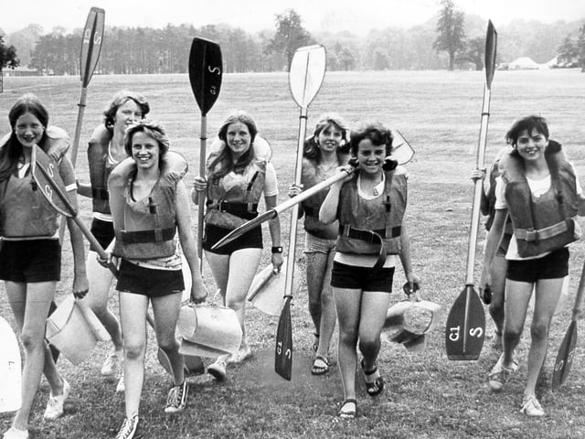 Girls from Ounsdale Comprehensive School in Wombourne and Gnosall Comprehensive School near Stafford prepare for a week of canoeing and camping in June 1975. Equipped with paddles and lifejackets, they were heading to the River Trent at Great Haywood for canoe tuition as part of a Staffordshire schools' outdoor education course at Shugborough. Do you remember taking part in school camping or outdoor adventure trips like this?