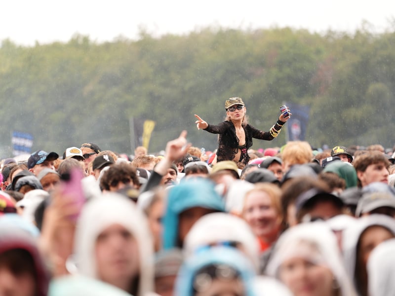A festival-goer gets a great view from her friend's shoulders in the crowd