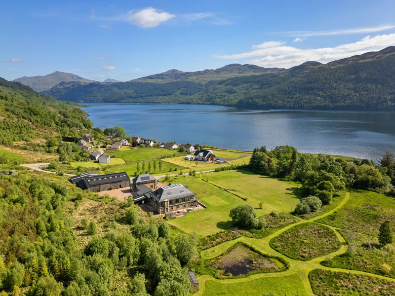 The principal Lodge includes eight bedrooms, a steam room, games room, multiple living spaces and a large open-plan kitchen. A formal dining room can accommodate up to 18 guests, while balconies and extensive glazing make the most of the surrounding landscape and views over Loch Goil.