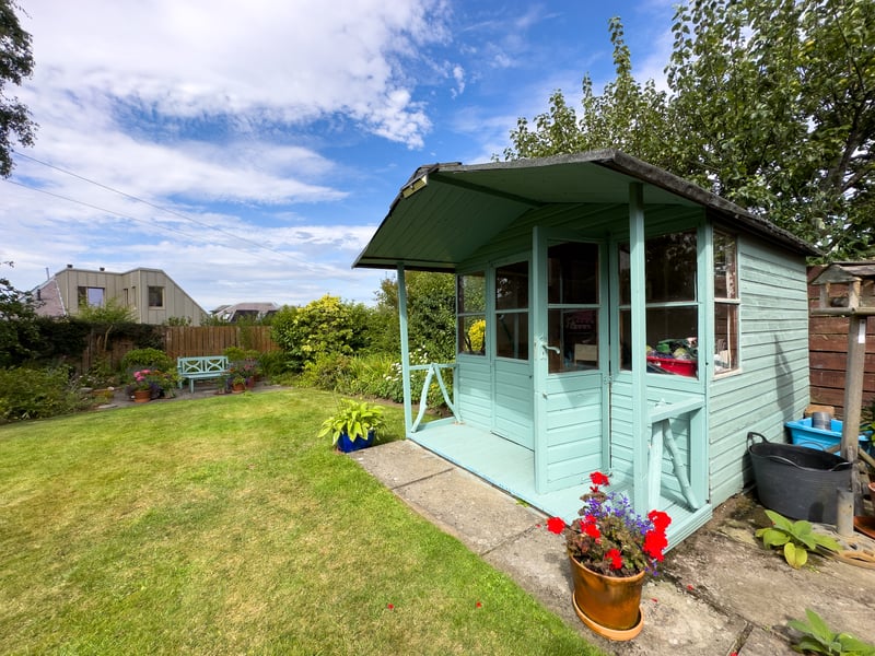 The rear garden has a large central lawn surrounded by established herbaceous borders, a summerhouse and a paved seating area.