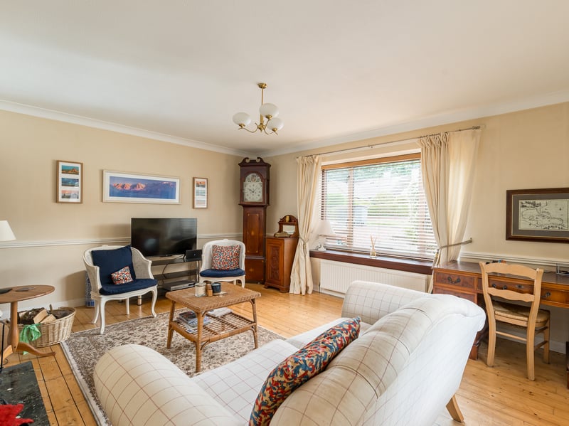 There is this sitting room with dual aspect windows and multi-fuel stove. As well as a kitchen with folding breakfast bar and door to the drive/garage.