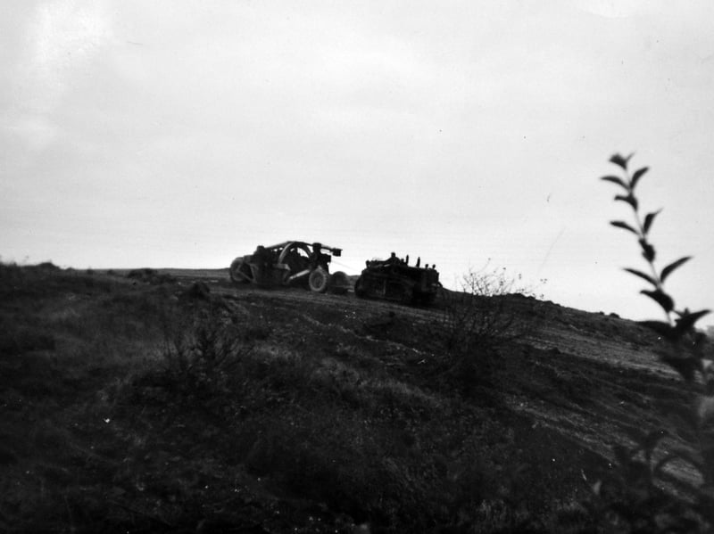 Heavy earthmoving machinery works atop the mound at Ketley in the early 1960s, clearing the landscape to make way for the construction of the Shropshire Star office and printworks. Shared by Mr John Whittingham, whose parents Alf and Sally Whittingham ran the local newsagents on Station Road, the photograph was likely taken from near their shop. It records a crucial moment of change as traditional industrial ground was transformed for the arrival of modern newspaper production. Do you remember the old mound at Ketley before work began, or do you recall buying your papers from Whittingham's newsagents back then?