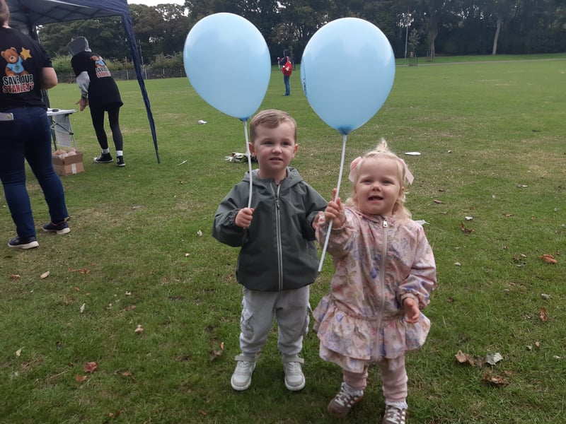 These two siblings enjoy playing with their balloons. 