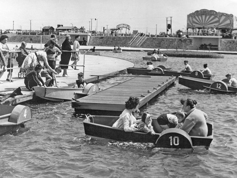 Families and children take to the water in small paddle boats at Chasewater in 1962, enjoying the newly built boating lake. Transformed into a booming leisure destination by Brownhills Urban District Council during the post-war era, the reservoir area quickly became a local seaside alternative for Black Country and Staffordshire residents. With fairground rides, a funfair canopy, and sun-baked promenades in the background, this cheerful scene captures the peak of summer holiday excitement close to home. Do you have fond memories of riding the paddle boats or visiting the fairground at Chasewater back in the 1960s?