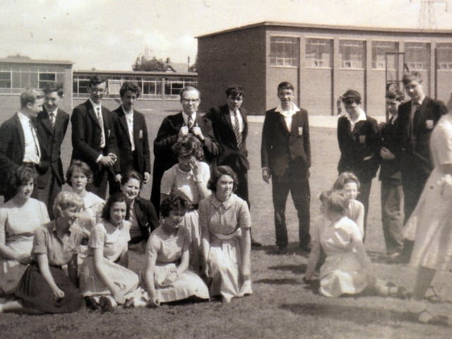 A group of pupils and teachers relax on the grass at Ounsdale School in Wombourne, captured in an informal, candid snapshot taken just after an official group photo was shot in 1962. Dressed in smart school blazers, ties, and summer dresses, the students share a lighthearted moment out in the sunshine, breaking character as the formal pose comes to an end. Opened in the mid-1950s, the modern comprehensive school quickly became a central landmark for the growing village community on the outskirts of the Black Country. Do you or someone in your family have memories of school days at Ounsdale in Wombourne during the 1960s?