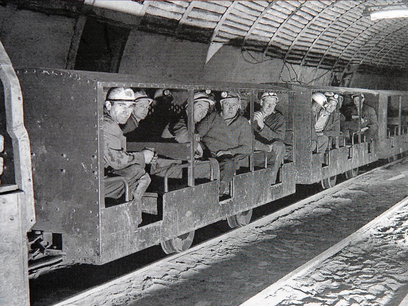Miners packed into underground manriding carriages head down the pit at Littleton Colliery in Huntington near Cannock around 1962. Fitted with helmets and cap lamps, the miners prepare for another long shift working the coal seams deep beneath Cannock Chase. As one of the largest and most prosperous collieries in the West Midlands coalfield, Littleton was a cornerstone of the local community, employing generations of miners who kept regional industry powered throughout the 20th century. Did you or any of your family work underground at Littleton Colliery or remember the coal mining era around Cannock?