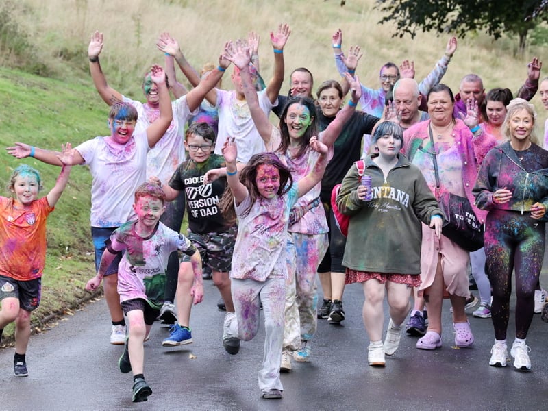 Colour Run participants put their hands in the air as they cross the finish line.