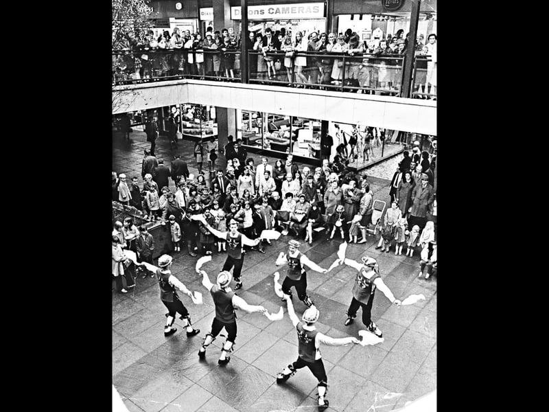 Members of The Green Man Morris and Sword Men perform an energetic traditional dance for a large crowd inside the Mander Centre on October 25, 1969. The lively display was part of a special fundraising day organised by the Tettenhall Friends of St Anthony's Cheshire Home in Penn. Spectators lined the upper galleries outside high street shops like Dixons Cameras and Lotus Shoes to watch the colourful spectacle, bringing traditional English folk culture into the heart of modern Wolverhampton. Do you remember watching live performances or charity displays in the Mander Centre back in the late 1960s?