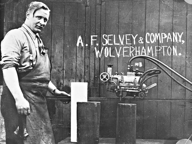 A proud Mr A F Selvey poses in his work apron alongside specialized machinery in July 1969, framed by a hand-drawn sign painted on a stable wall in St Mark's Street. Operating under the name A F Selvey & Company, the small metal fabrication and engineering outfit represented the modest, hardworking beginnings of a local business. Through skilled craftsmanship and dedicated trade, the firm established its footing amidst Wolverhampton's vibrant manufacturing landscape during the post-war era. Do you or your family remember the small engineering workshops and fabrication yards around St Mark's Street?
