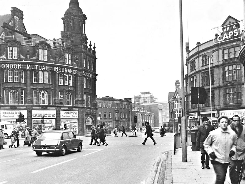 Pedestrians cross the road and shoppers go about their day in February 1969, captured in a vibrant view looking down Lichfield Street towards Stafford Road. Dominating the left of Princes Square is the magnificent architecture of the Royal London Mutual Insurance Society building, with Greys Television Centre and Electrical shop occupying the ground floor. Across the way, storefronts including Fleet Electrics and a Capstan cigarettes sign frame the bustling town centre, showcasing a classic slice of daily life in 1960s Wolverhampton. Do you remember visiting Greys or Fleet Electrics when shopping around Princes Square back in 1969?