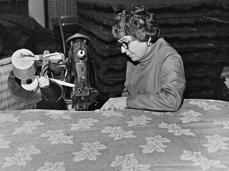 Seated at an industrial sewing machine, Dorothy Yardley operates the edge-taping mechanism to assemble a floral-patterned mattress cover at Bagnalls Ltd in August 1969. The intricate process involved marrying the fabric cover to its internal assembly while simultaneously piping and taping the edges together - a task requiring considerable dexterity and experience. Highlighting the skilled craftswomen behind Wolverhampton's textile and bedding industries, the image offers an authentic look into local workshop production during the post-war era. Do you or any of your relatives remember working at Bagnalls Ltd or in Wolverhampton's upholstery and bedding trades during this period?