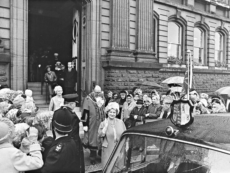 Queen Elizabeth The Queen Mother offers a warm wave to cheering crowds as she steps out to her official car in June 1969. Walking just behind her in civic robes is the Mayor of Wolverhampton, Alderman Stanley Tatem, along with local dignitaries and police escorts guiding the royal visitor. Despite the wet weather, with onlookers lining the pavement under umbrellas and headscarves, the town turned out in force to give the beloved royal figure an enthusiastic send-off during her visit to Wolverhampton. Do you remember turned out in the rain to catch a glimpse of the Queen Mother during her 1969 visit to Wolverhampton?