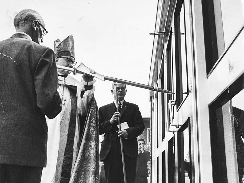 The Bishop of Lichfield, the Right Rev. Arthur Reeve, uses his pastoral staff to knock on the entrance doors of St Matthew's Church in Wolverhampton during its official opening and consecration ceremony in July 1969. Dressed in full ceremonial vestments and accompanied by church wardens and civic attendees, the Bishop performed the traditional ritual to request entry before leading the congregation inside. The ceremonial occasion marked a significant milestone for the local parish community as they officially dedicated their modern new place of worship. Do you remember attending the consecration service or visiting St Matthew's Church during its opening year in 1969?
